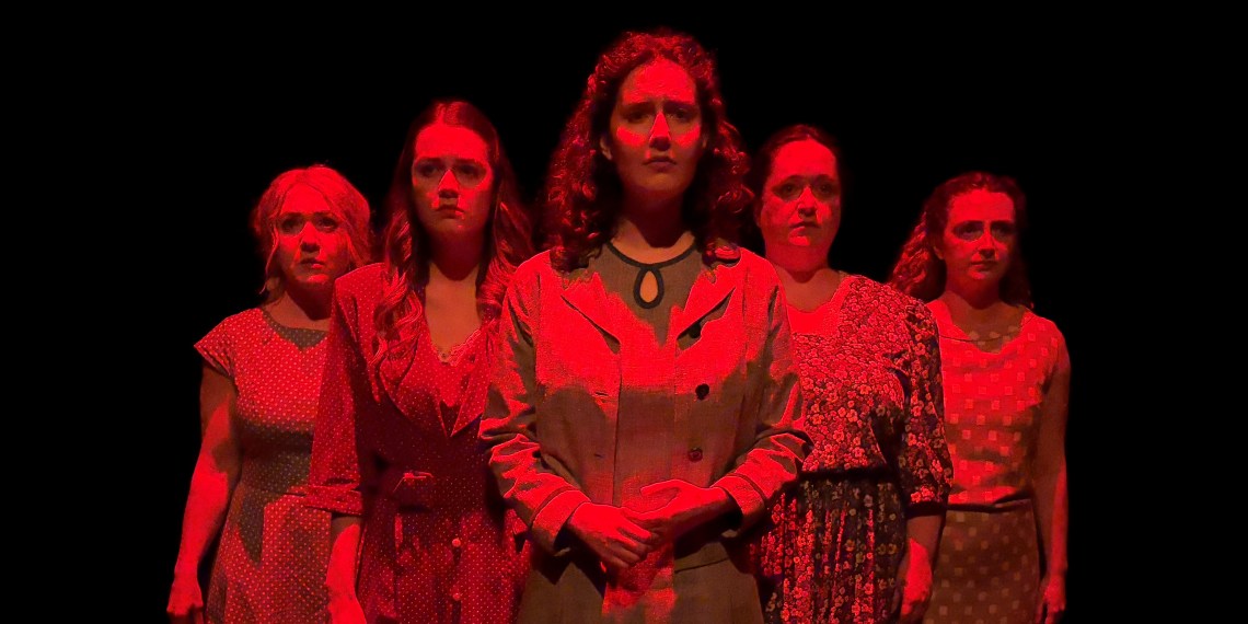 Five women dressed in 1940s costumes stand together, lit by a dark red light.